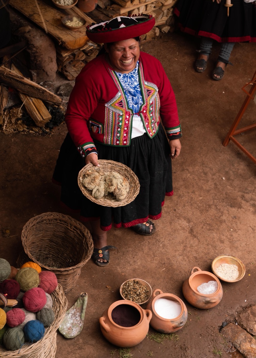 Augusta Pumacahua Pumayali smiling while presenting natural dye materials and wool at a Colores de Abundancia workshop, Chinchero, Peru