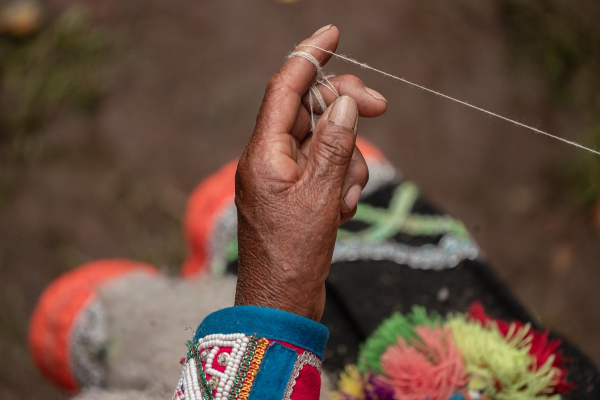 Close-up of an artisan's hands spinning thread at a Colores de Abundancia gathering, Chinchero, Peru