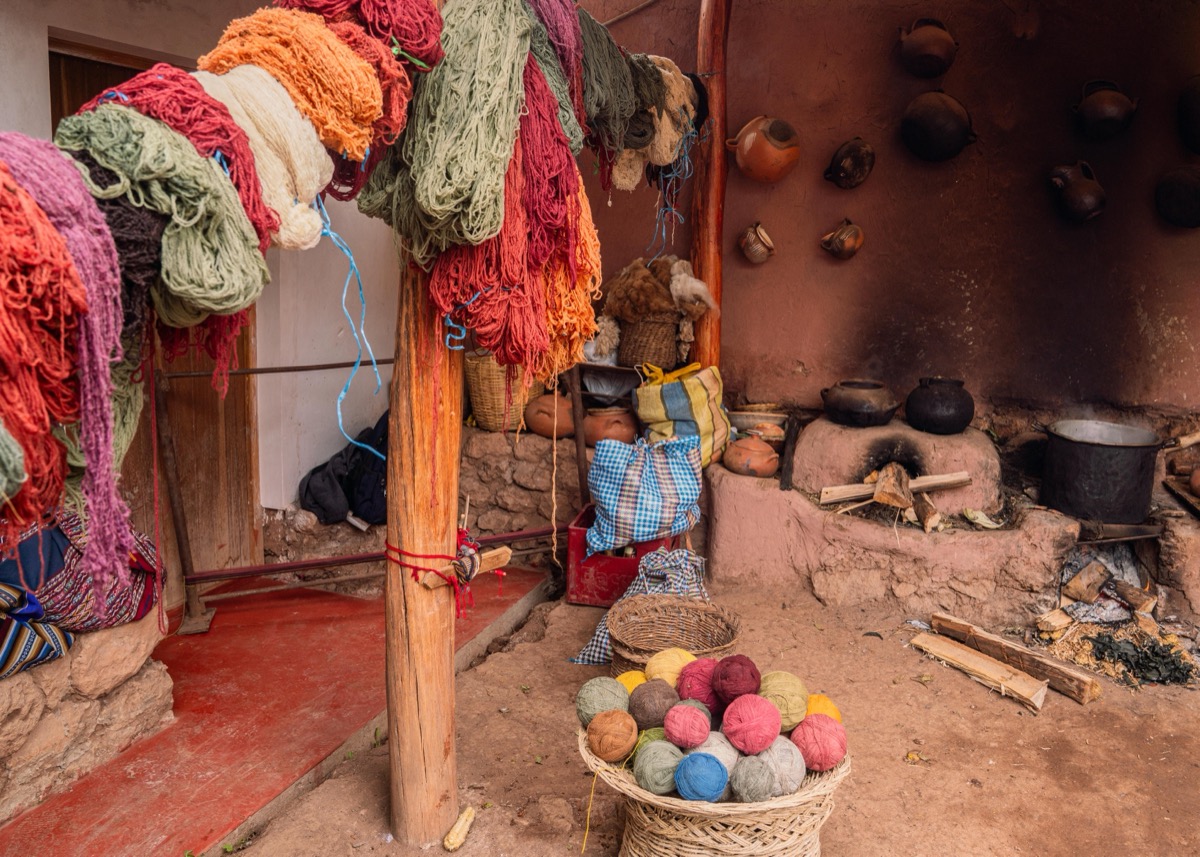 Naturally plant-dyed yarn hanging to dry alongside a basket of hand-dyed wool balls at a Colores de Abundancia workshop, Chinchero, Peru