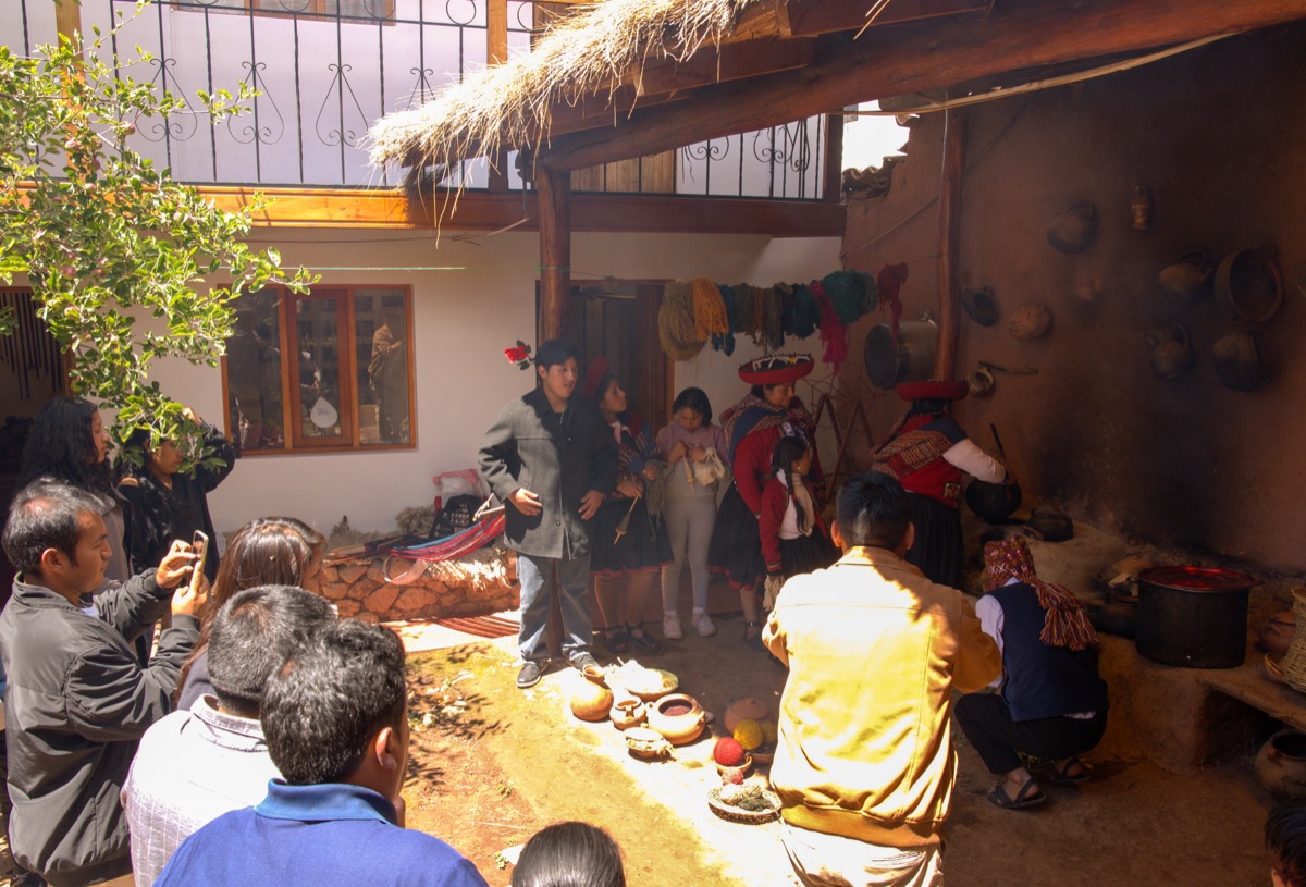 A Colores de Abundancia workshop gathering in a traditional Chinchero courtyard, with artisans and visitors gathered around a demonstration