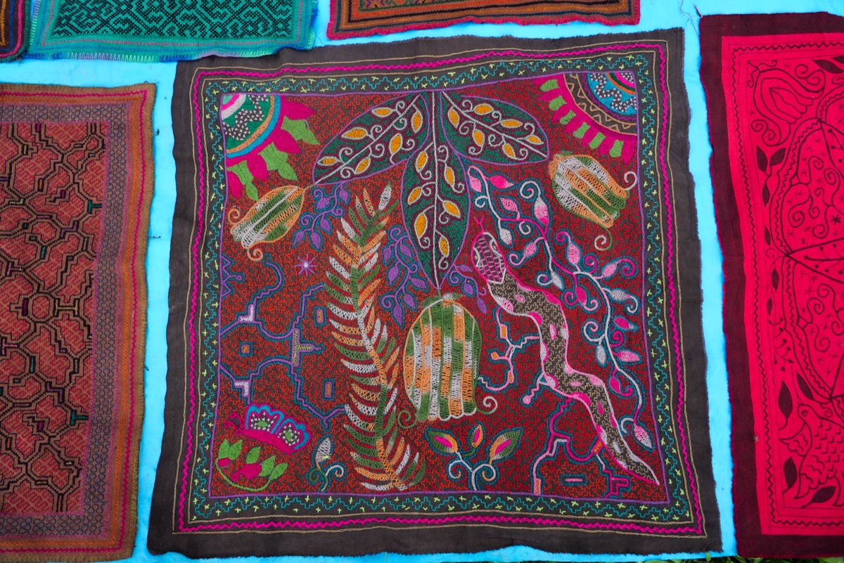 Kené embroidery piece by Ida Castro Rojas with intricate floral and animal motifs in rich colors on dark fabric, Paohyan, Peru