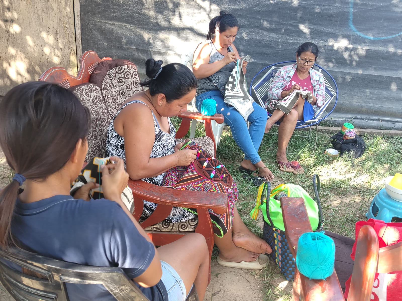 Shipibo-Konibo women from Paohyan sitting outdoors embroidering kené designs on clothing together, Loreto, Peru