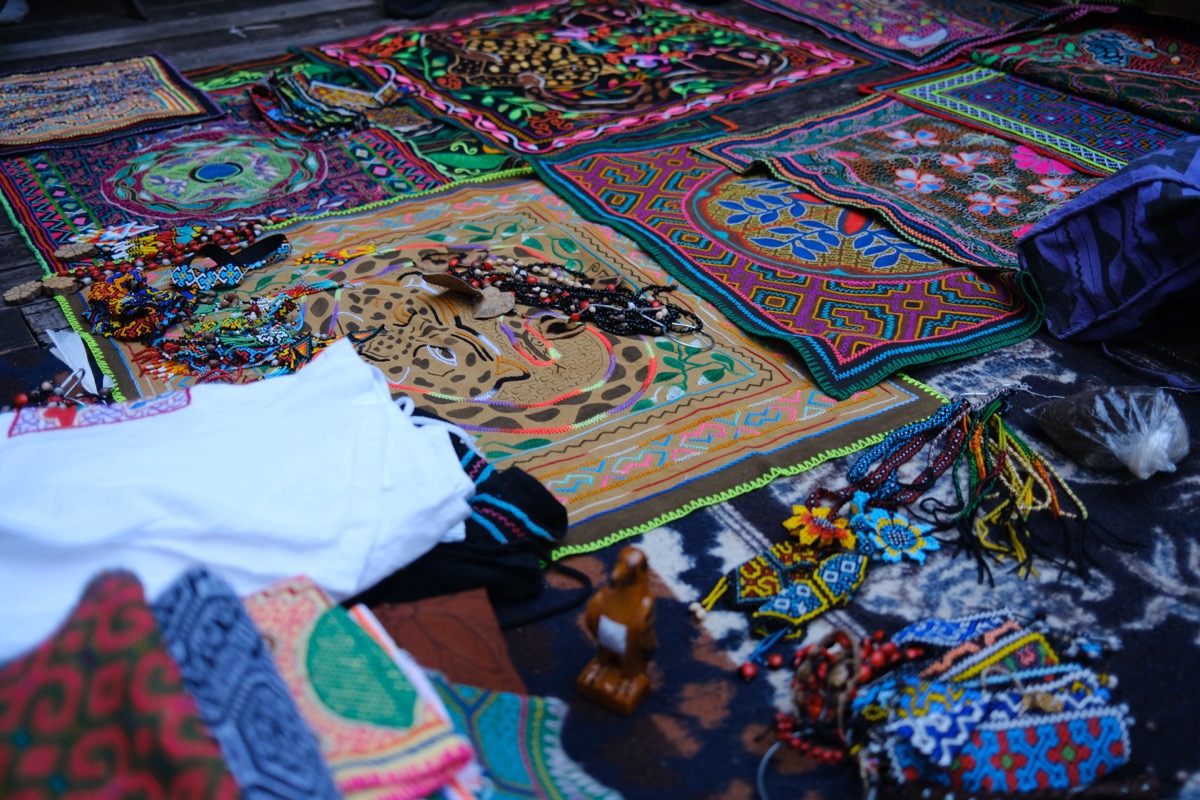 Colorful kené embroidered textiles and beaded artesanías by Shipibo-Konibo artists laid out on display, Calleria, Pucallpa, Peru