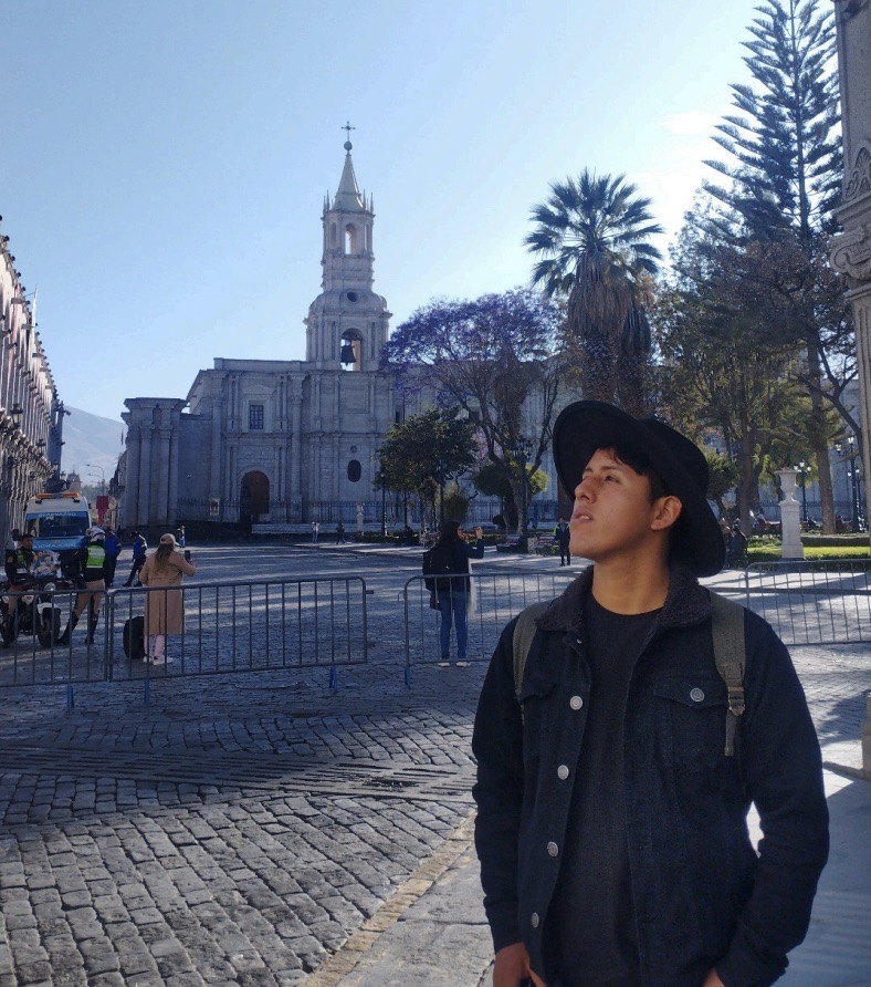 Robert Singona Pumacahua, muralist and weaver from Chinchero, standing in a Peruvian plaza